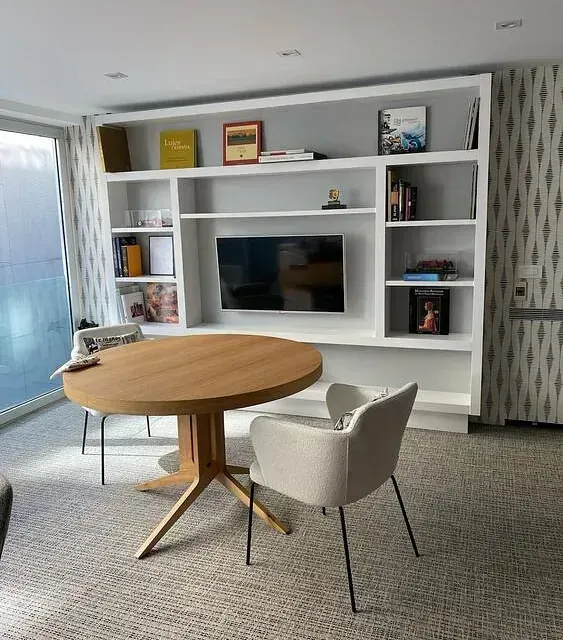 Una sala de estar con una mesa redonda y sillas y un televisor de pantalla plana.