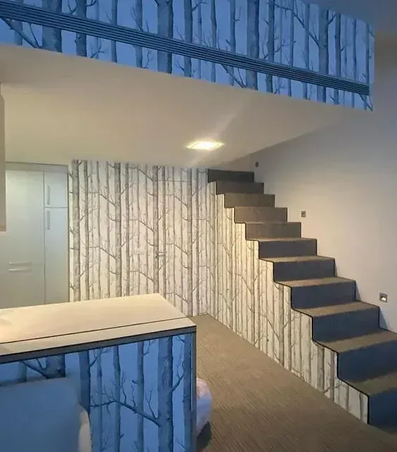 Una escalera en una habitación con árboles en la pared.