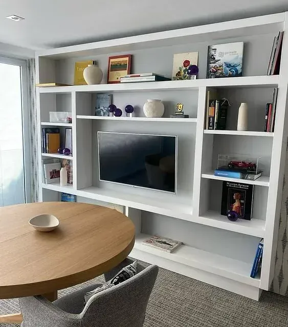 Una sala de estar con una mesa redonda y un televisor de pantalla plana.