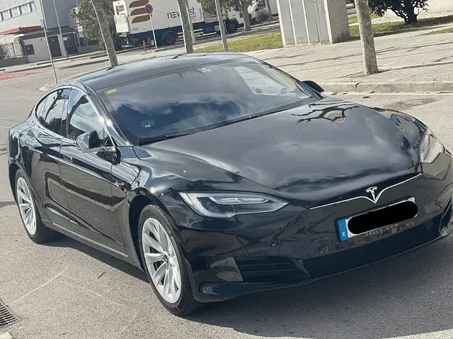 Un sedán Tesla Model S negro estacionado en una calle de la ciudad, durante el día.