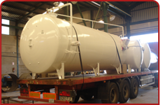 Un gran tanque blanco está sentado encima de un remolque rojo.