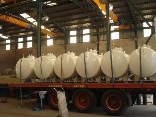 Una fila de barriles blancos se encuentran encima de un remolque de carga rojo.