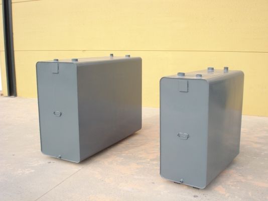 Dos cajas grises están en el suelo frente a una pared amarilla.