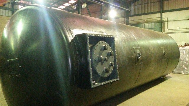 Un gran tanque de metal está en el suelo en un almacén.