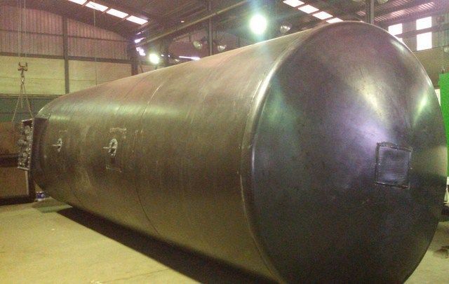 Un gran tanque de acero inoxidable se encuentra en un almacén.