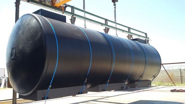 Un gran tanque negro está siendo levantado por una grúa.