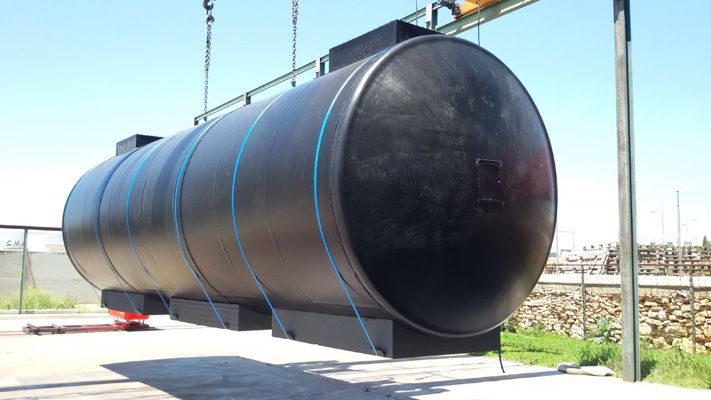 Un gran tanque negro está siendo levantado por una grúa.