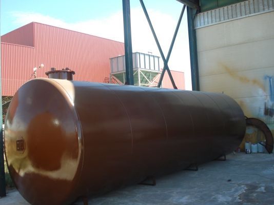 Un gran tanque marrón se encuentra frente a un edificio.