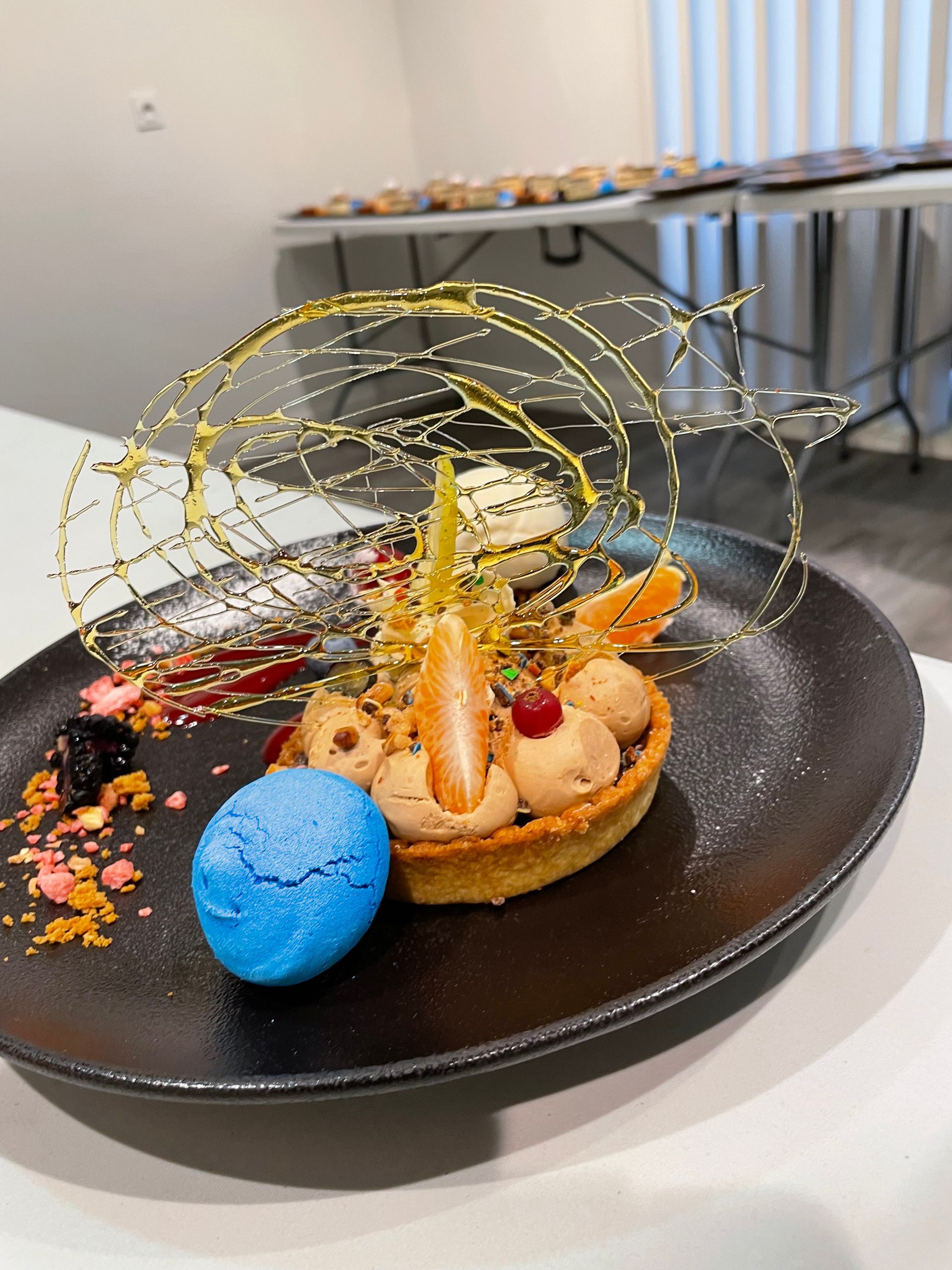 Dessert avec macaron bleu, mousse pralinée et décor en sucre filé