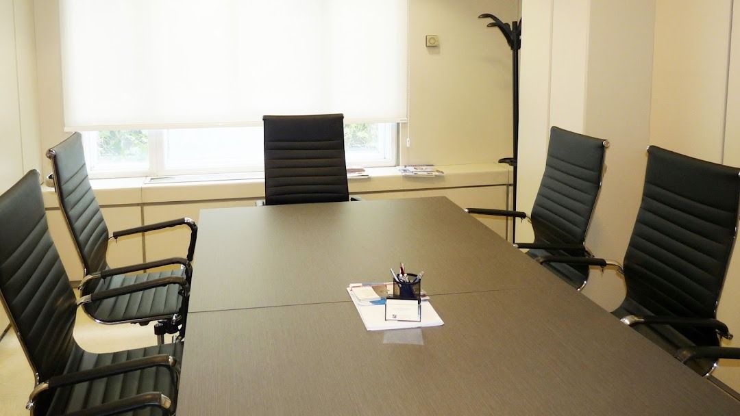 Sala de conferencias con mesa oscura, sillas negras y una ventana.