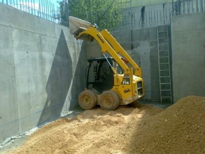 Una excavadora amarilla está cargando tierra en una pila.