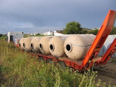 Una fila de barriles de hormigón se encuentran en un remolque en un campo.