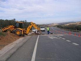 Una excavadora amarilla está parada al costado de una carretera.
