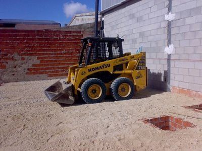 Una excavadora Komatsu está estacionada frente a una pared de ladrillos