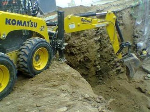 Un tractor Komatsu amarillo está cavando un hoyo en la tierra.