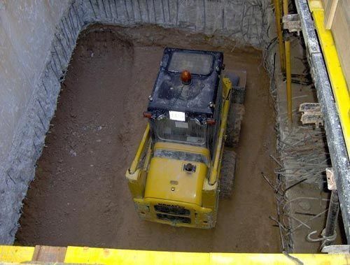 Una excavadora amarilla está estacionada en un pozo de tierra
