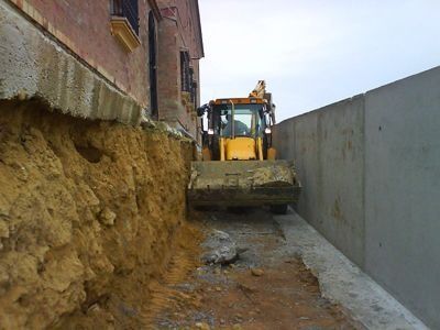 Una excavadora amarilla está cavando un hoyo en el suelo frente a un edificio.