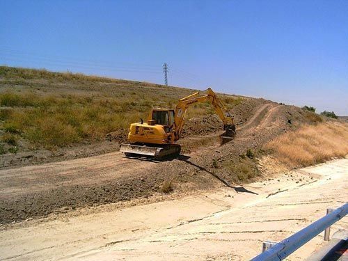 Una excavadora amarilla está trabajando en un camino de tierra