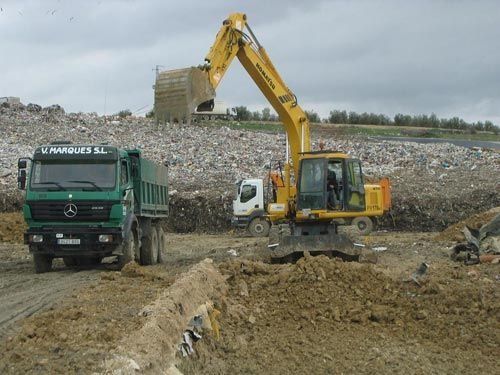 Una excavadora amarilla está cargando tierra en un camión volquete.