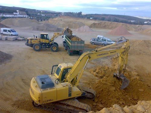 Una excavadora amarilla está cargando tierra en un camión volquete.