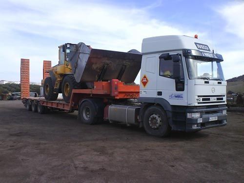 Un camión semirremolque con un tractor en la parte trasera.