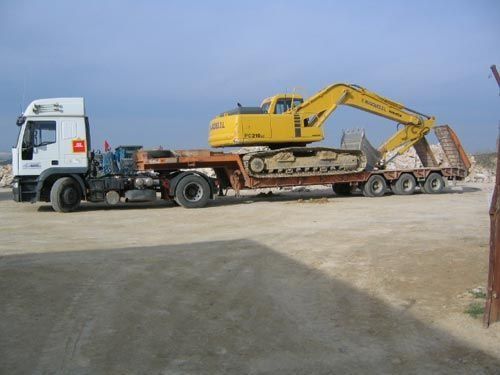 Una excavadora amarilla está en la parte trasera de un camión semirremolque