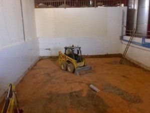 Una pequeña excavadora amarilla está parada en una habitación llena de tierra.