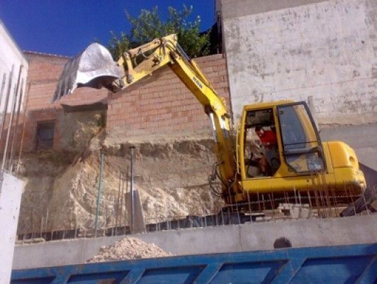 Una excavadora amarilla está cargando tierra en un contenedor de basura.