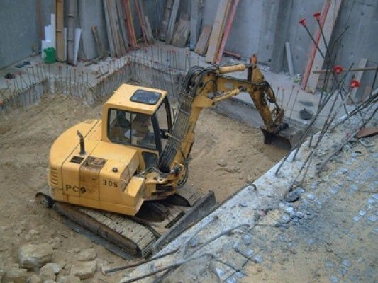 Una excavadora amarilla está cavando un hoyo en un sitio de construcción.
