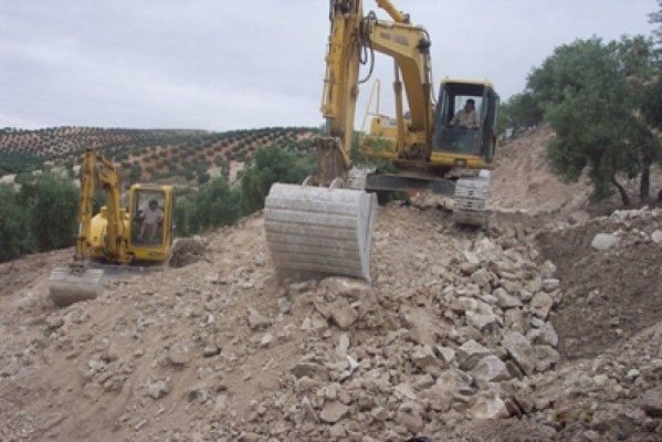 Una excavadora amarilla está cavando en una pila de rocas