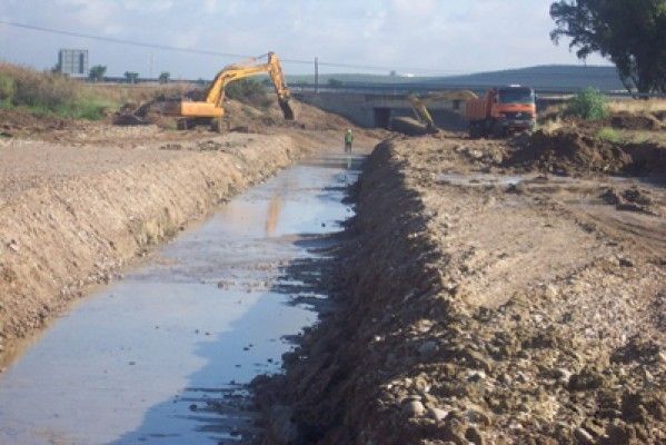 Una excavadora amarilla está trabajando en un camino fangoso.