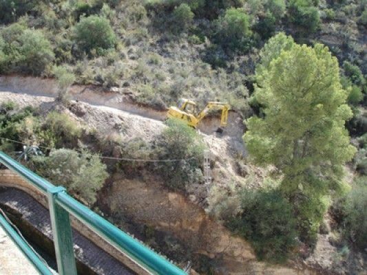 Una excavadora amarilla está trabajando en la ladera de una colina.