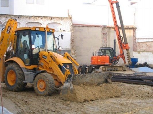 Un tractor JCB amarillo está trabajando en un sitio de construcción.