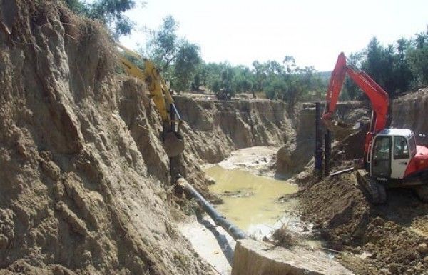 Una excavadora está cavando un hoyo en la tierra cerca de un río.