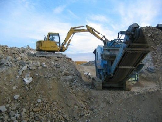 Una excavadora amarilla está trabajando en una pila de rocas.