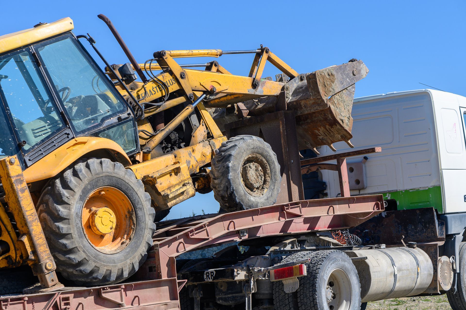 Un tractor amarillo está sentado encima de un remolque.