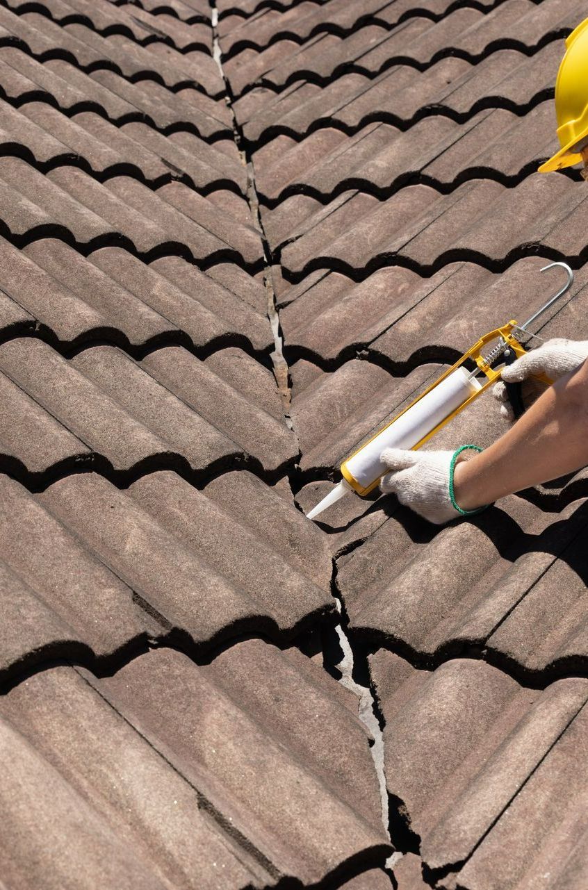 Un couvreur met un produit sur le toit pour améliorer l'étanchéité