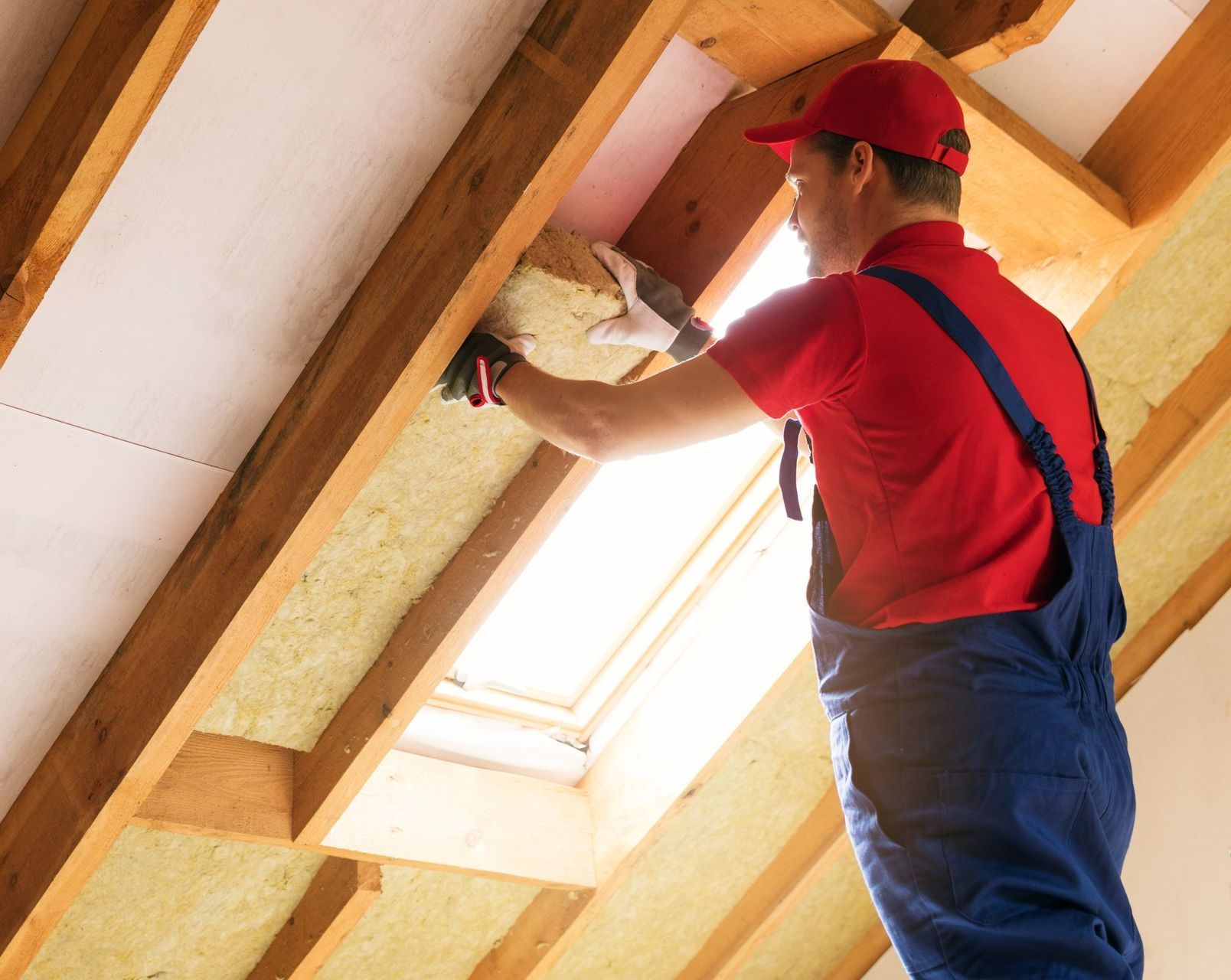 Un artisan pose de la mousse isolante
