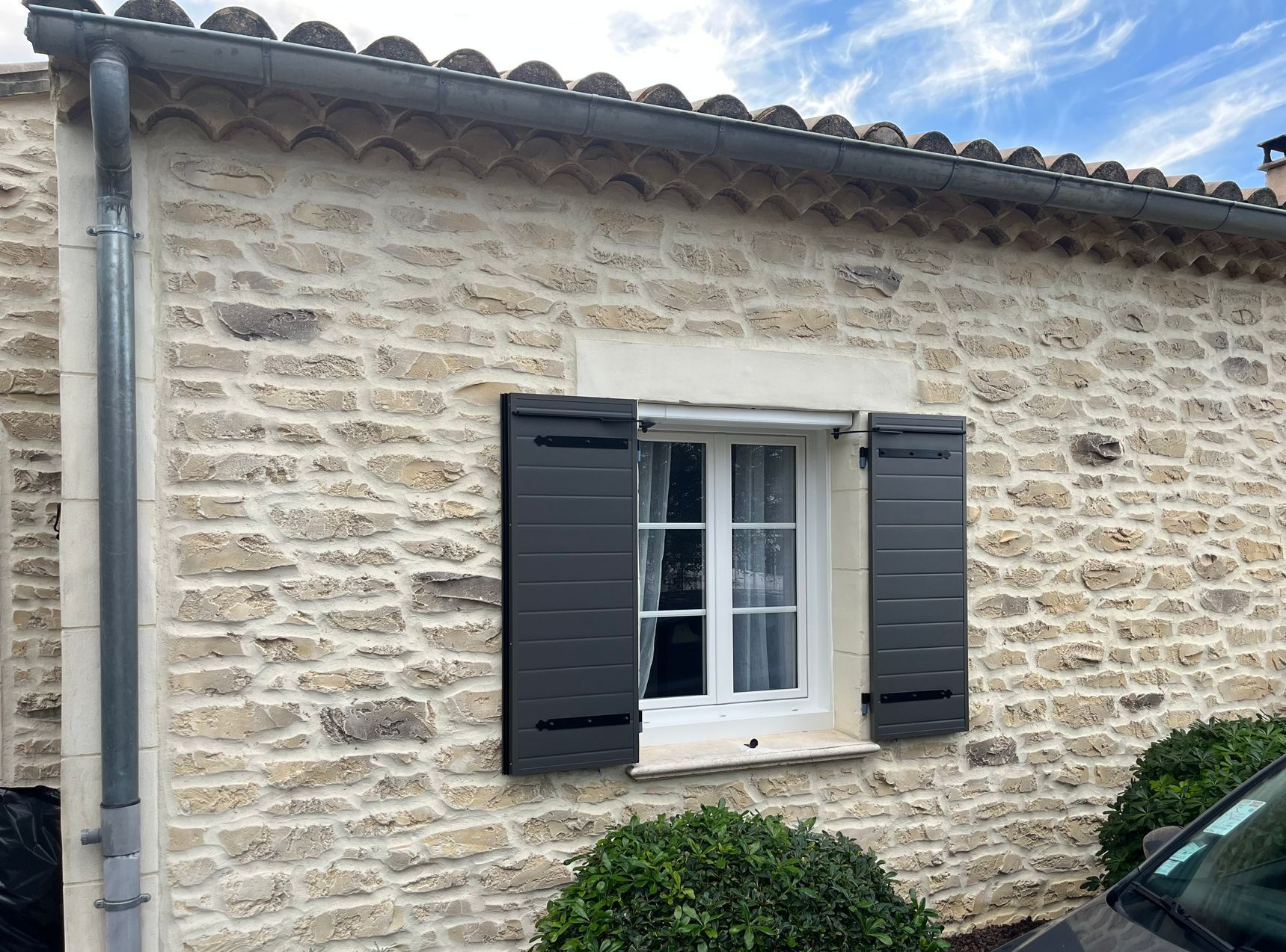 Volets noirs contre un mur en pierre