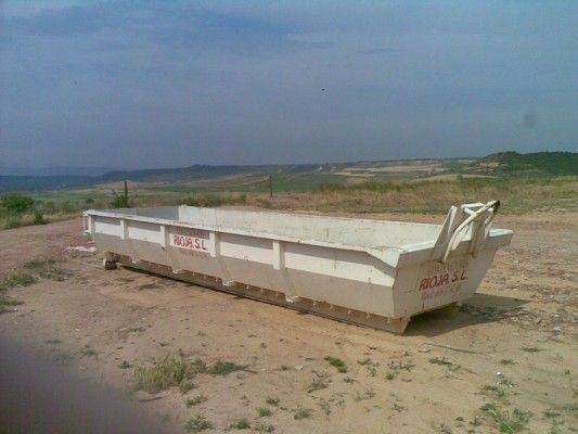 Un gran contenedor de basura blanco en una polvorienta obra en construcción bajo un cielo nublado.