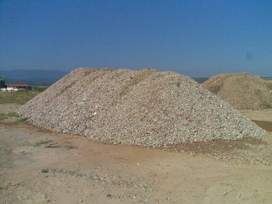 Gran montículo de grava o arena en un campo abierto y polvoriento bajo un cielo despejado.