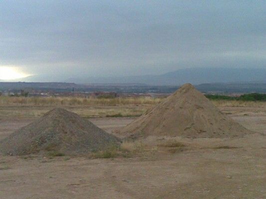 Dos montículos de tierra en un campo árido bajo un cielo nublado.