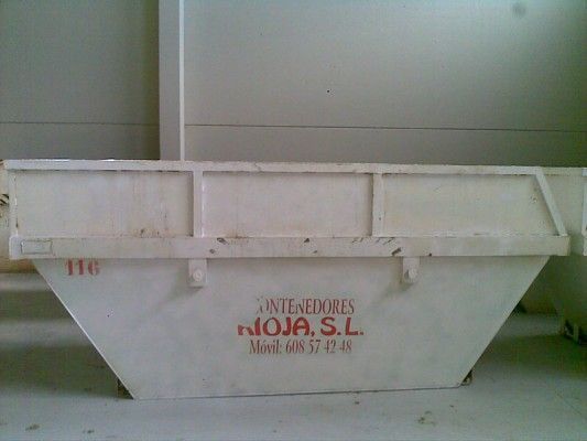 Contenedor industrial blanco con letras rojas sobre una pared lisa.