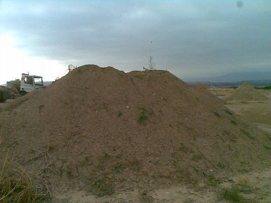 Gran montículo de tierra en un campo árido bajo un cielo nublado.