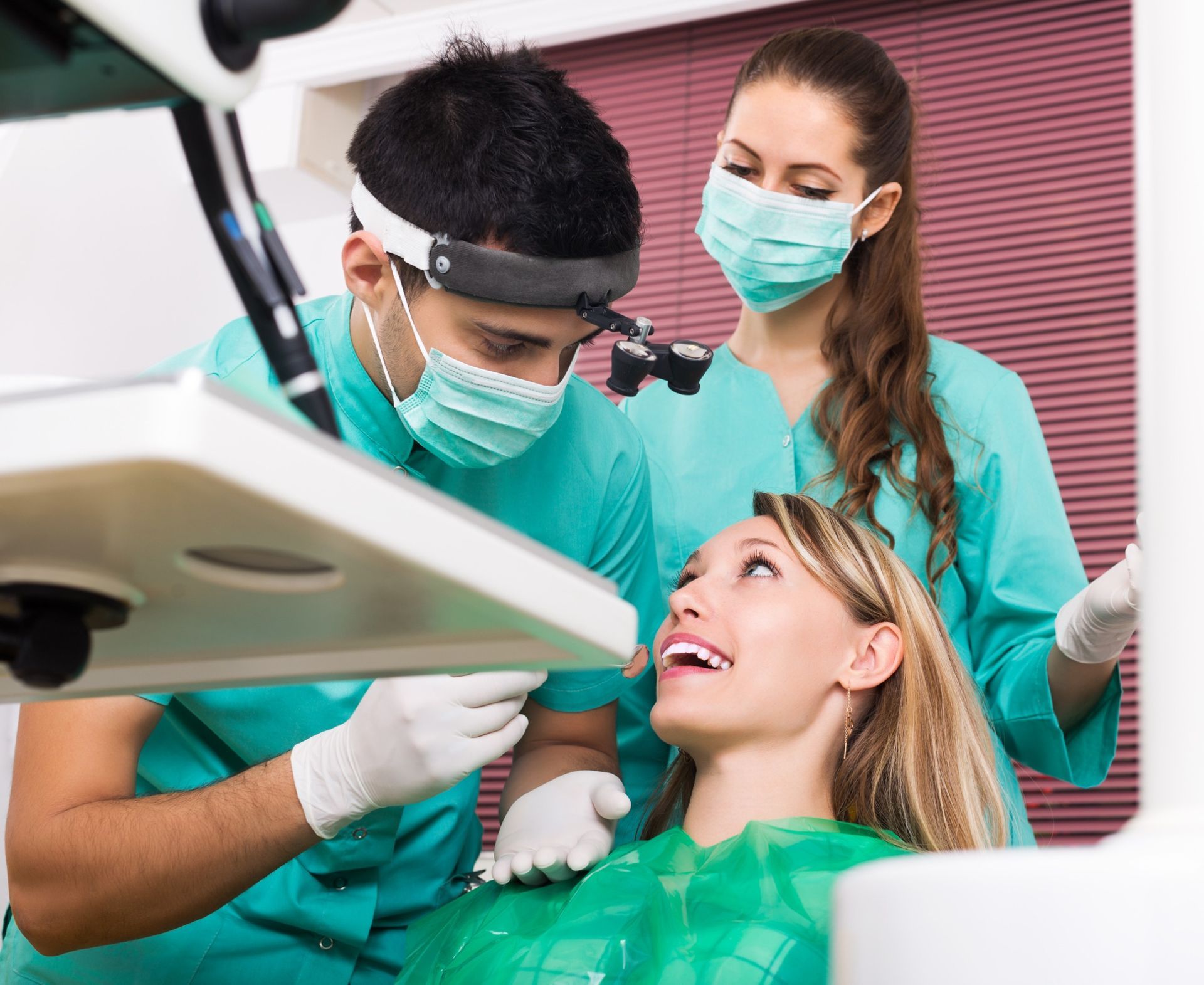 Una mujer está sentada en una silla dental mientras un dentista le examina los dientes.