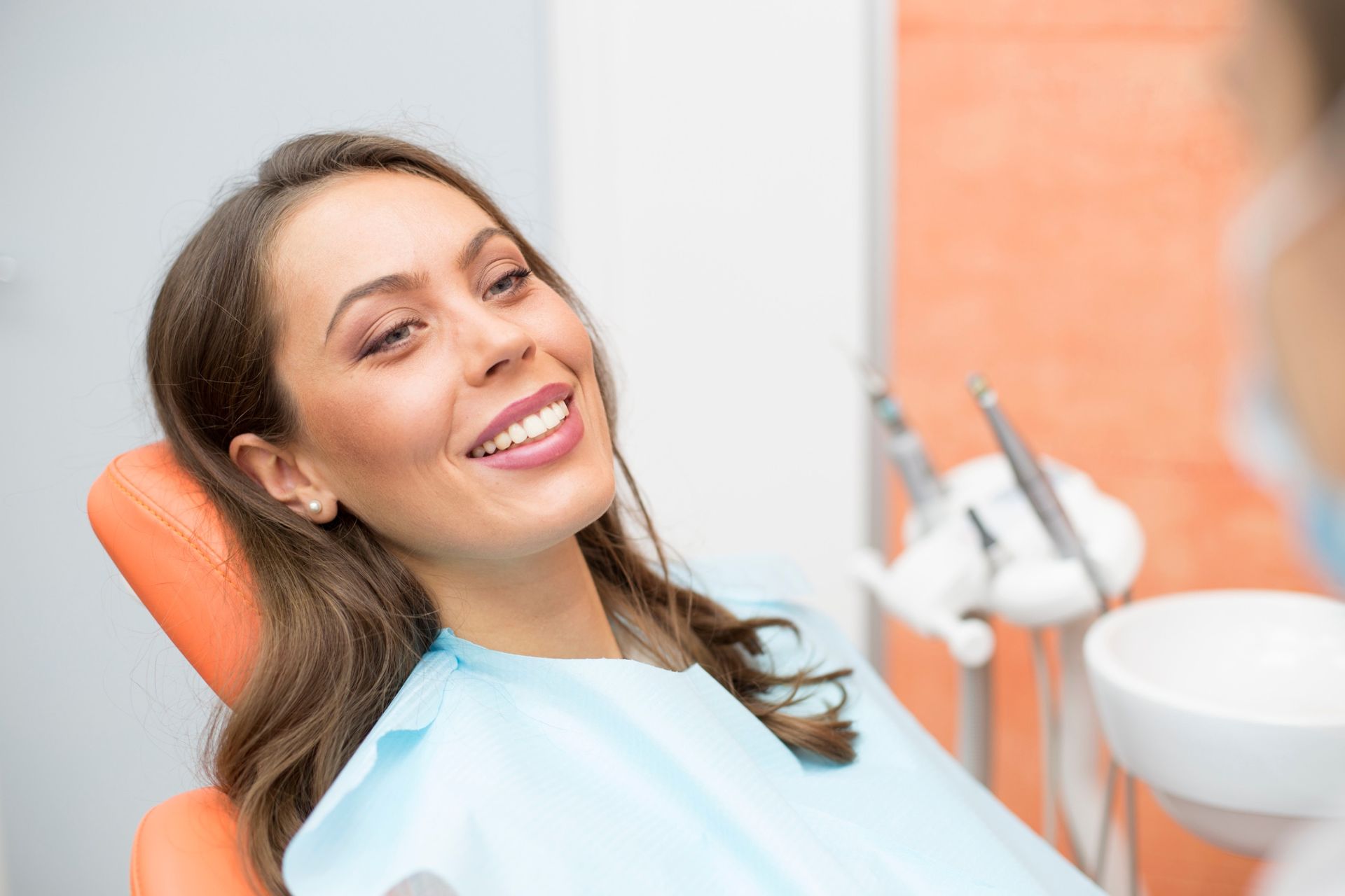 Una mujer sonríe mientras está sentada en una silla dental.