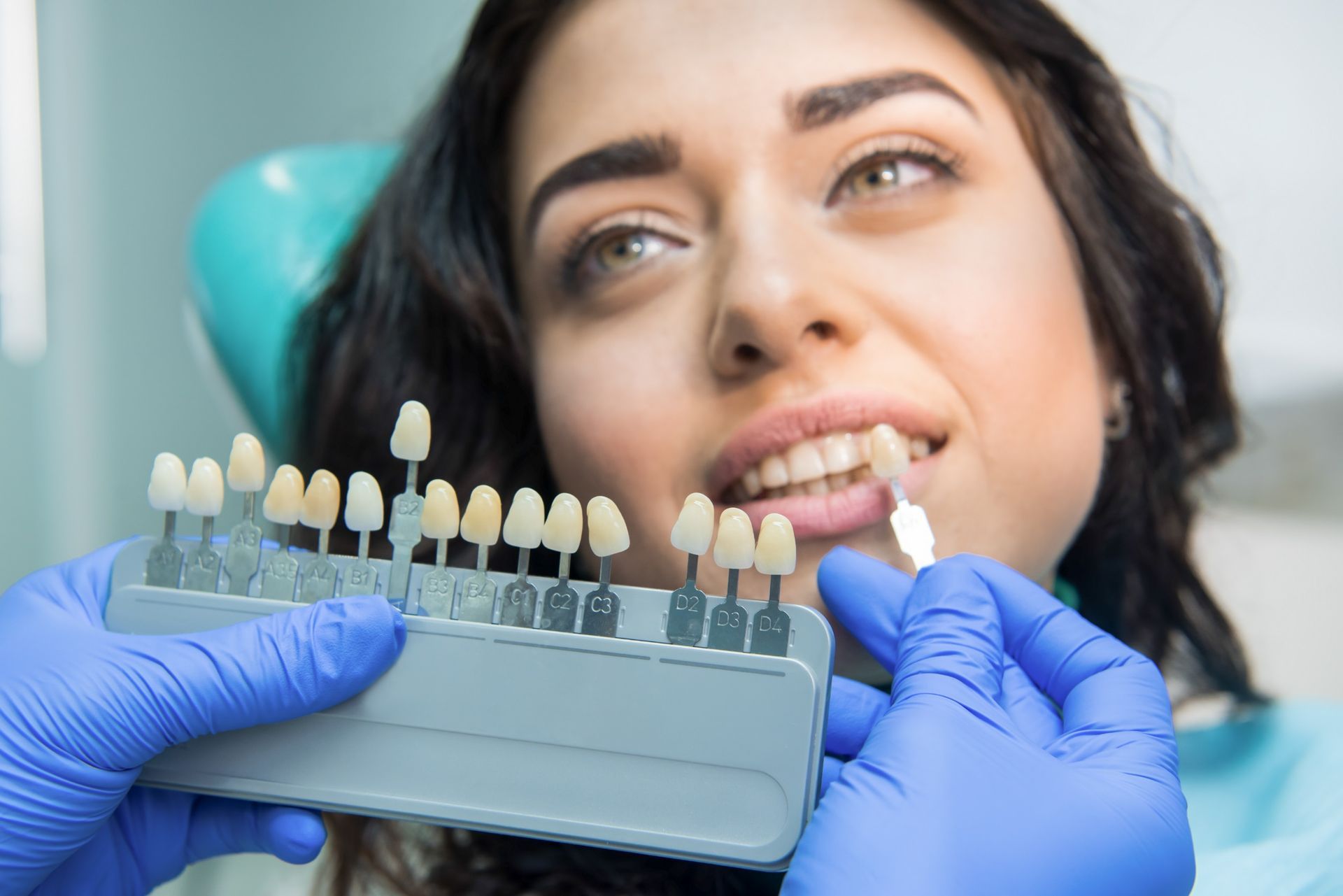 Una mujer está sentada en una silla dental mientras un dentista le examina los dientes.