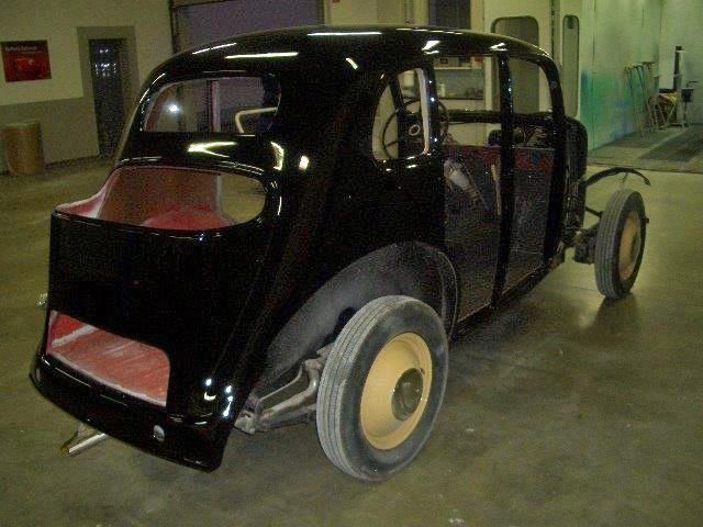 Ein schwarzes Auto mit einem gelben Rad steht in einer Garage