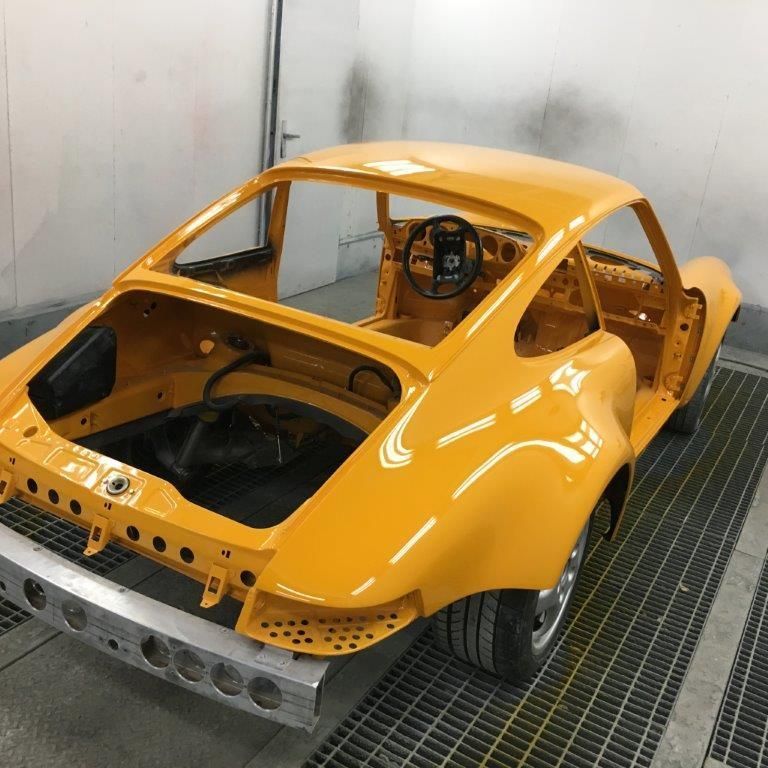 Ein gelbes Auto steht mit offenem Kofferraum in einer Garage