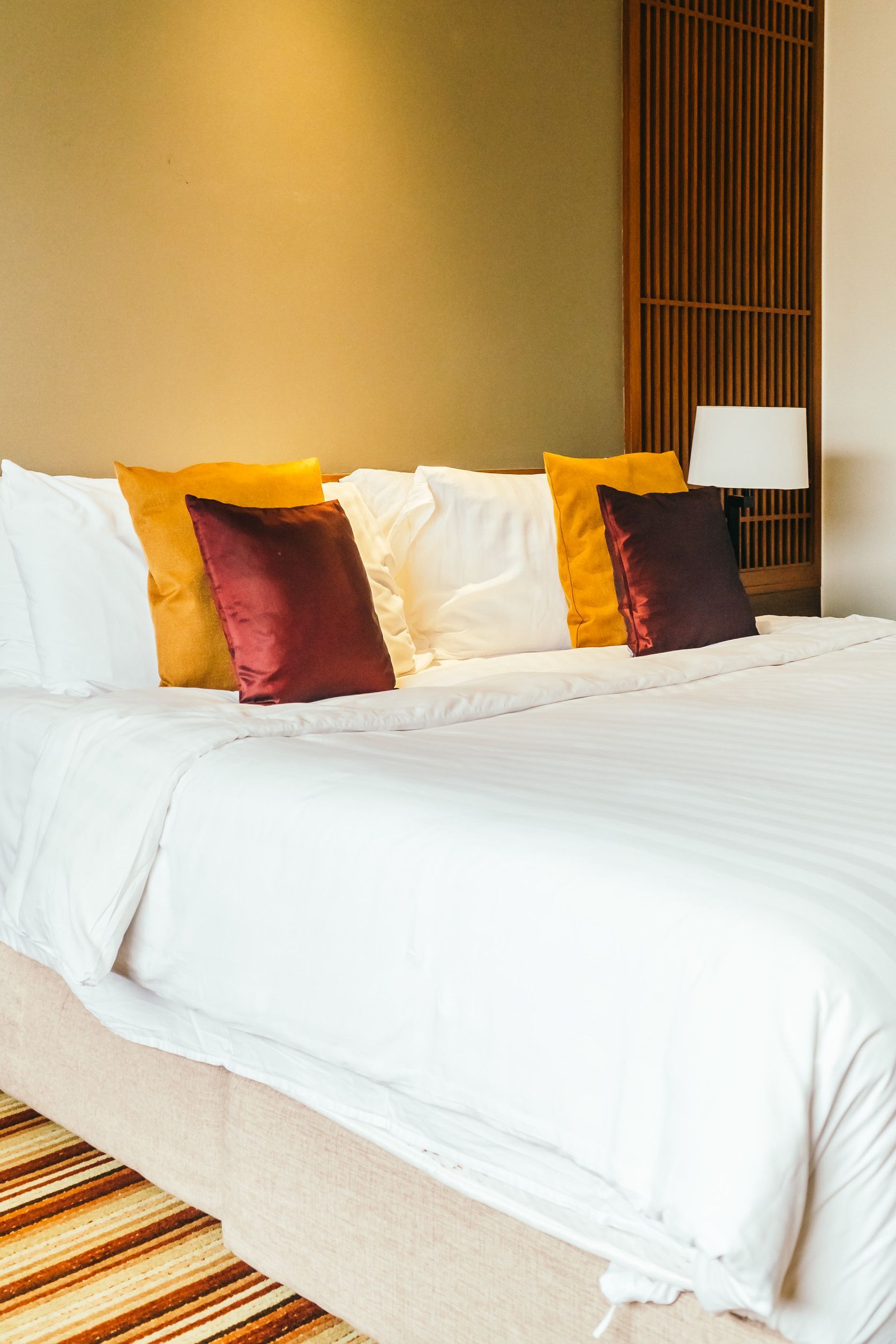 Una cama con sábanas blancas y almohadas en una habitación de hotel.